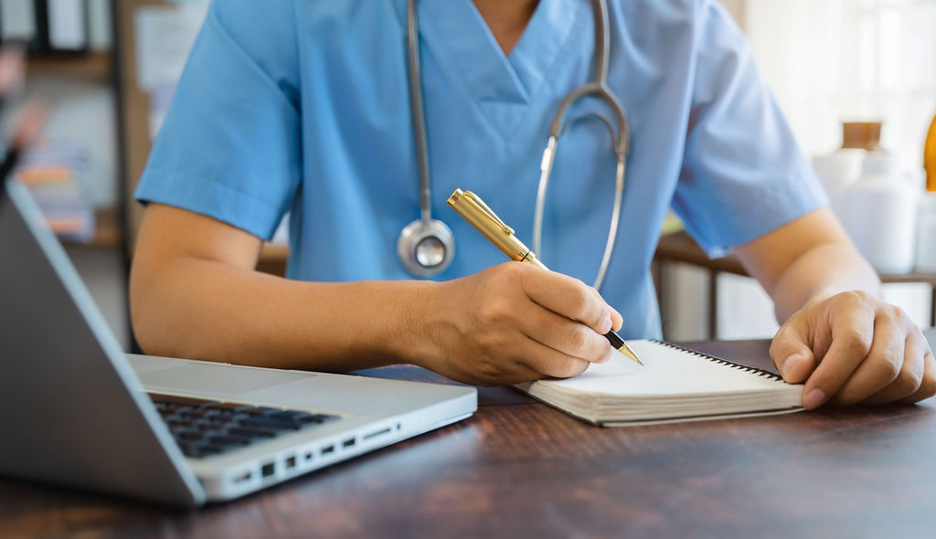 A clinician reviewing notes at a laptop
